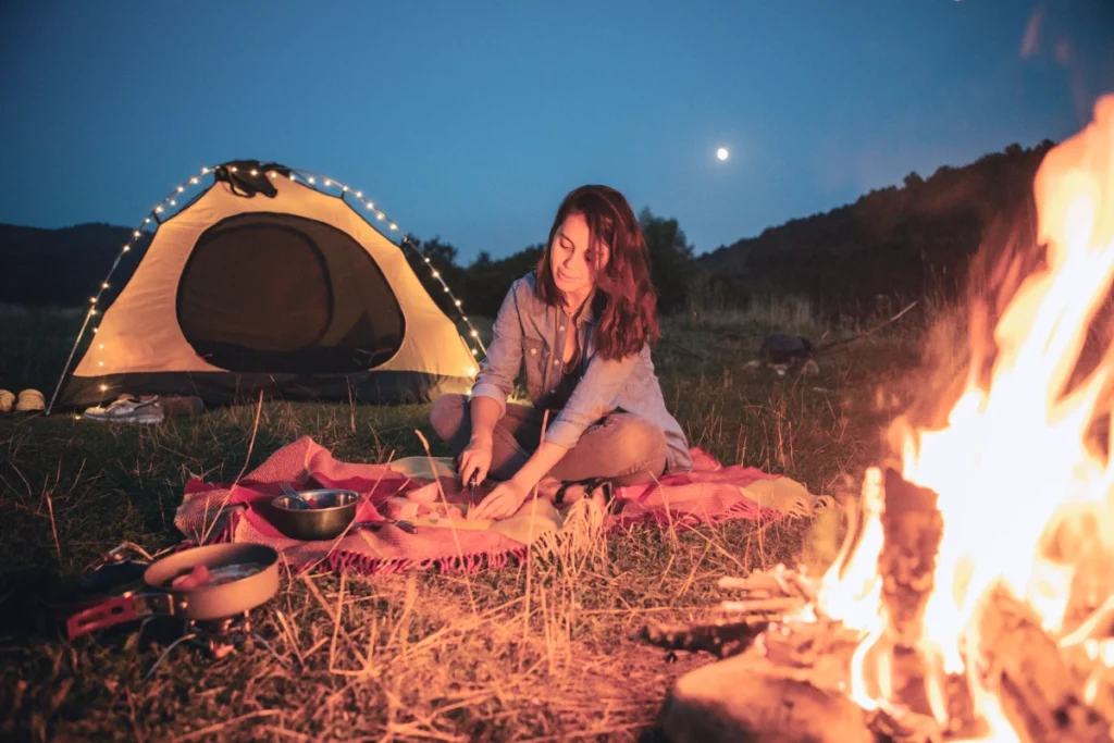 a photo of a woman camping alone at night with a camp fire