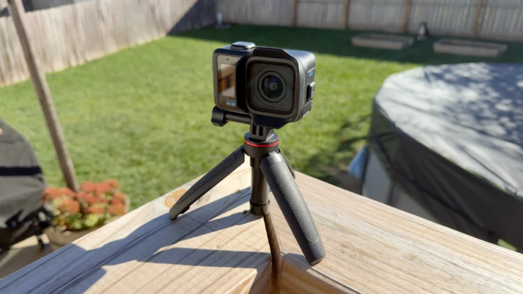 GoPro Mission 1 Pro camera mounted on a small black tripod on a backyard deck rail